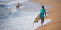 Kovalam, Chennai, Tamilnadu, India - Ã¢â¬Å½Ã¢â¬Å½August 9th Ã¢â¬Å½2021: Small Indian boy surfer carrying surfboard and walking on the beach